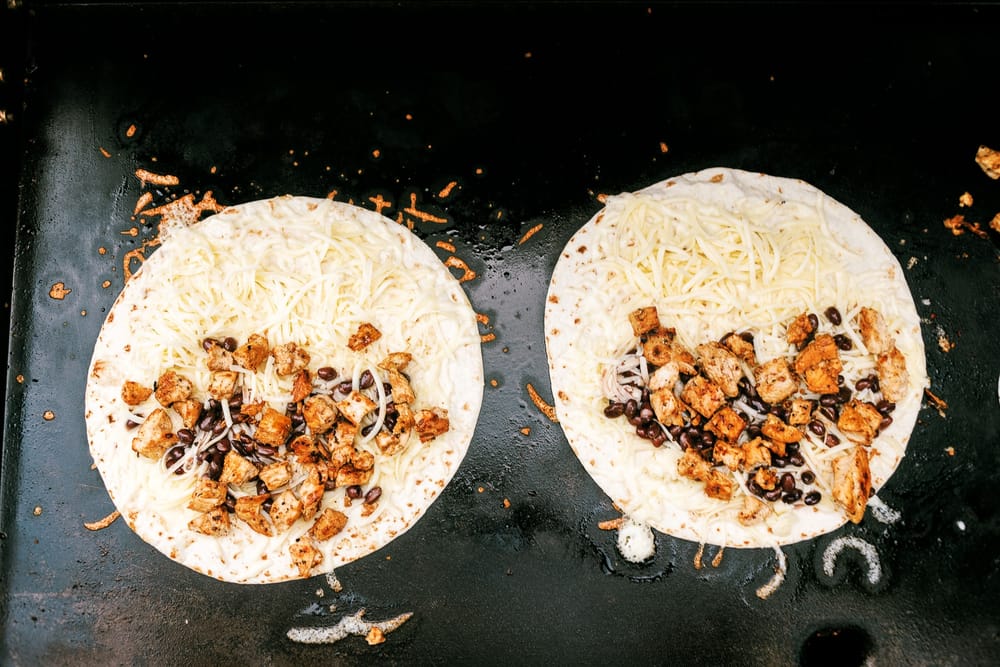 Blackstone chicken quesadillas cooked on a flattop grill stuffed with savory chicken, melted Monterey cheese, and flavorful black beans. Its the perfect quick weeknight meal!