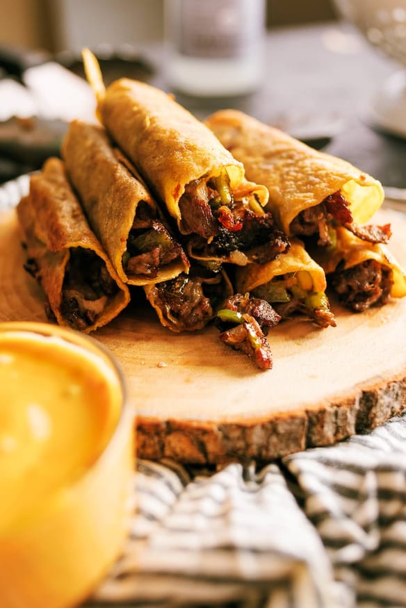 Philly cheesesteak taquitos recipe with thinly sliced ribeye steak, cheese, onions and bell pepper grilled on the Blackstone griddle. 
