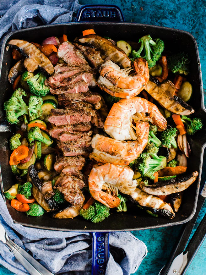 A Surf n' Turf Paleo bowl with Steak and Shrimp, over bell peppers, shallots, portabella mushroom, zucchini with a savory seasoning.