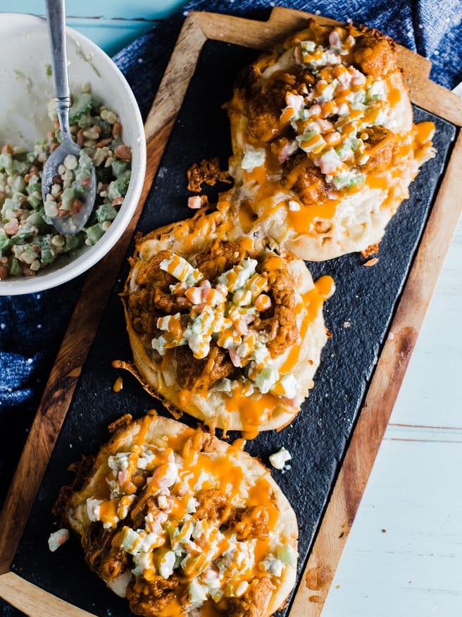 An buffalo chicken flatbread pizza, that is topped with a celery and carrot bleu cheese slaw. Easy dinner night and makes a perfect game day lunch!