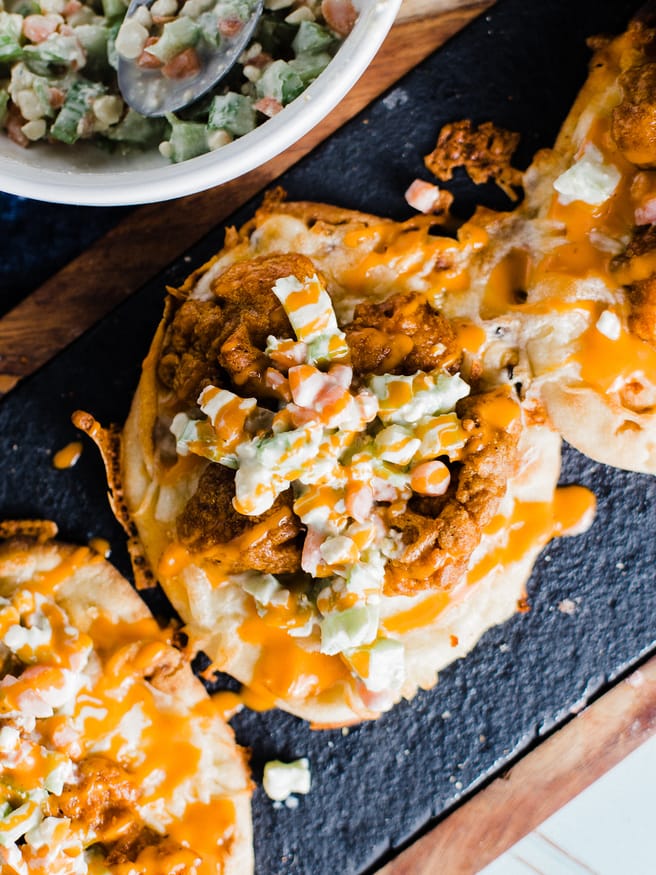 An buffalo chicken flatbread pizza, that is topped with a celery and carrot bleu cheese slaw. Easy dinner night and makes a perfect game day lunch!