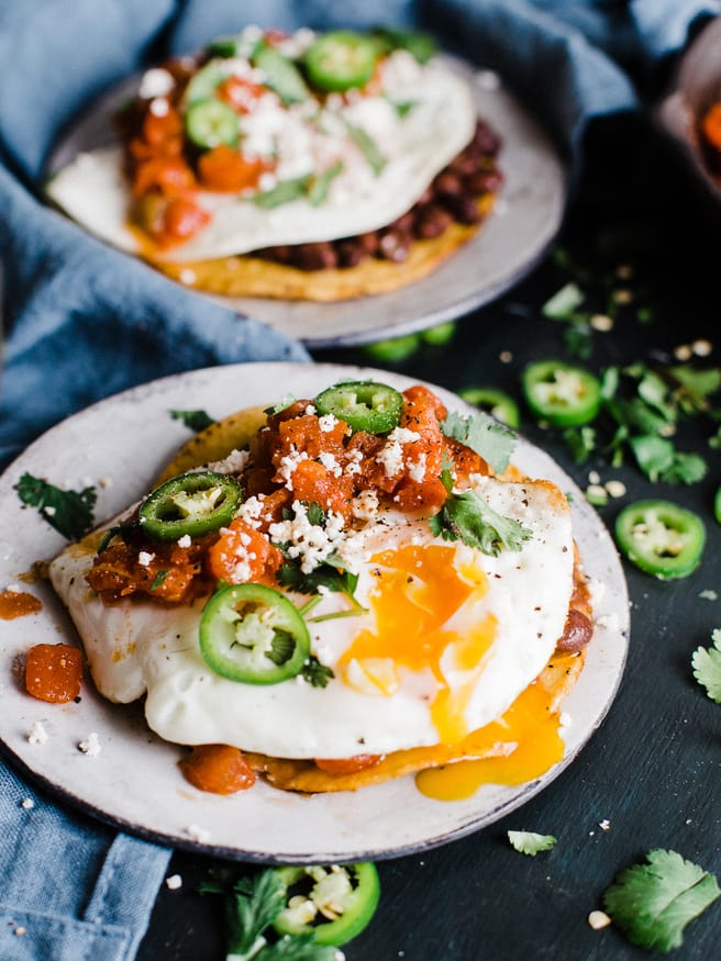 Huevos Rancheros Tostadas makes a great breakfast for dinner, or bunch meal. Topped with black beans, a from scratch salsa, then topped with a fried egg cojita cheese and serrano peppers
