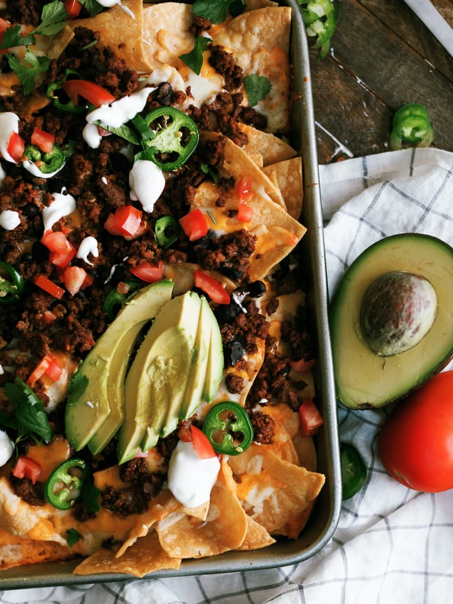 Taco Night Sheet Pan Nachos are a great way to put a spin on taco night. Taco seasoned ground beef and all your favorite taco toppings on sheet pan nachos.
