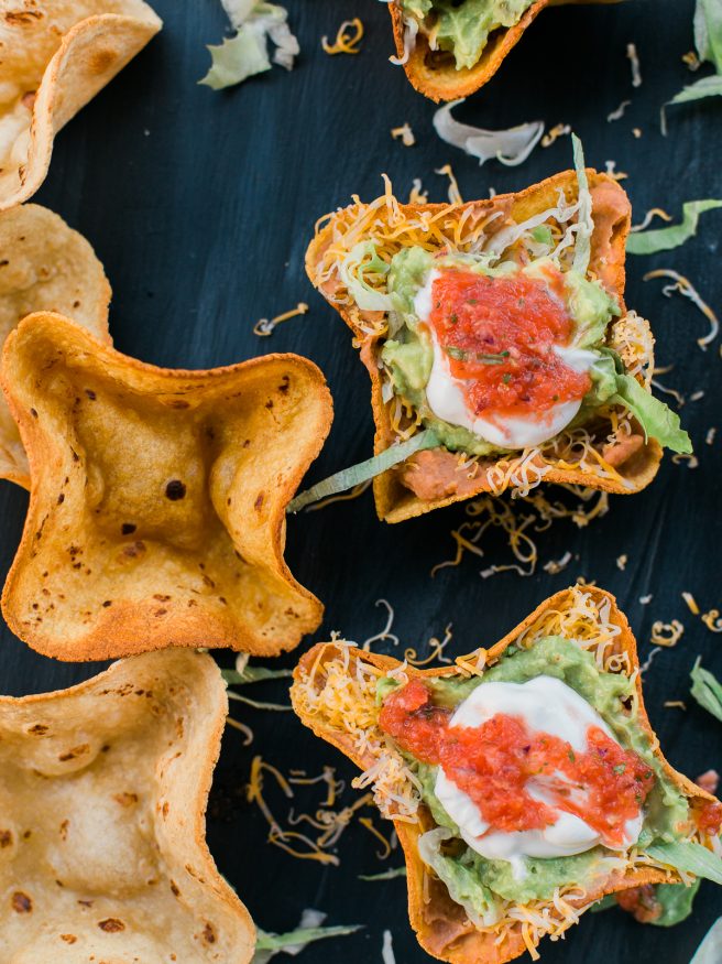 Homemade tostada bowl filled with 7 layer bean dip fillings making this a perfect weeknight meal or even for game day!