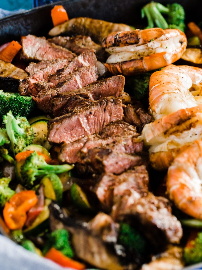 A Surf n' Turf Paleo bowl with Steak and Shrimp, over bell peppers, shallots, portabella mushroom, zucchini with a savory seasoning.