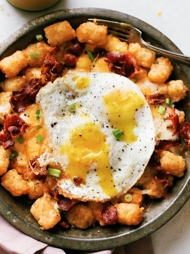 Tater Tots loaded up with bacon, cheese and green onion, then topped with a couple fried eggs. Great breakfast for dinner idea!