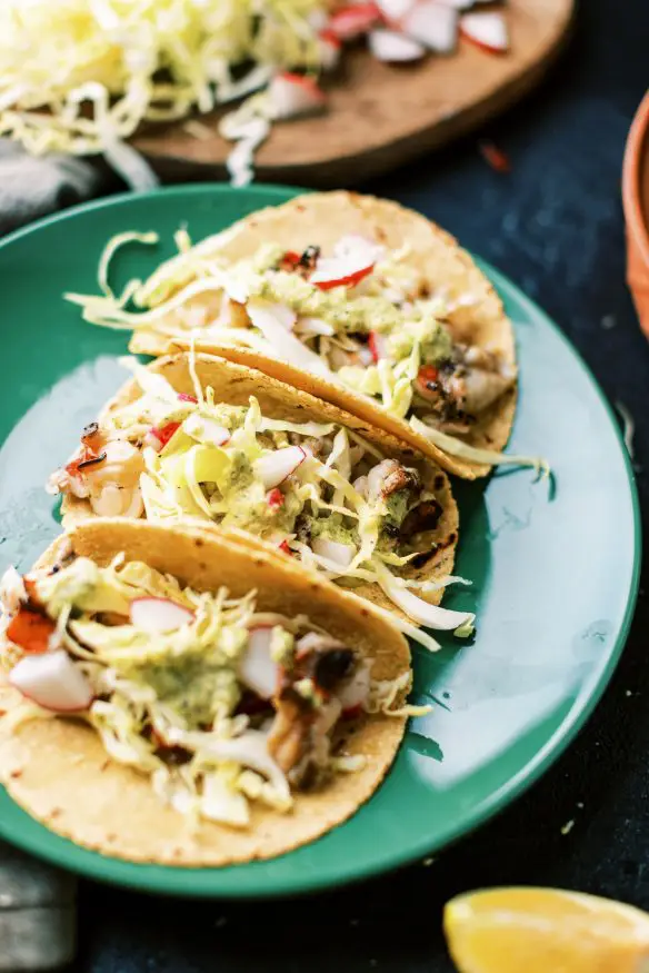 Grilled lobster tacos with lobster tails that are basted in a butter and garlic. garnished with cabbage and a spicy serrano pepper sauce.