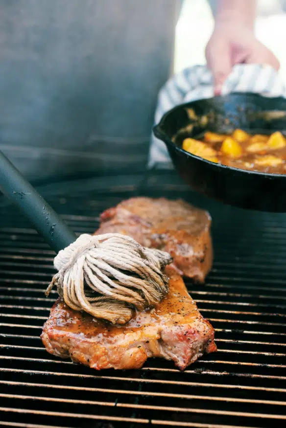 low and slow smoked pork chops topped with a peach glaze that is out of this cooked down with a little bourbon that makes a killer dinner!