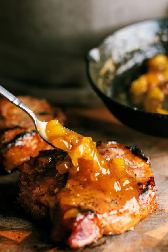 low and slow smoked pork chops topped with a peach glaze that is out of this cooked down with a little bourbon that makes a killer dinner!