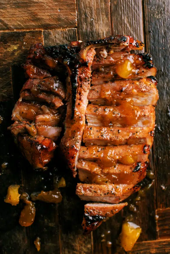 low and slow smoked pork chops topped with a peach glaze that is out of this cooked down with a little bourbon that makes a killer dinner!