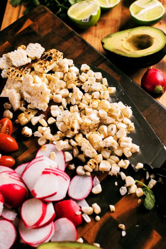 A seared steak salad topped with a fresh cilantro lime vinaigrette topped with fire roasted corn, ripe cherry tomatoes and radishes.