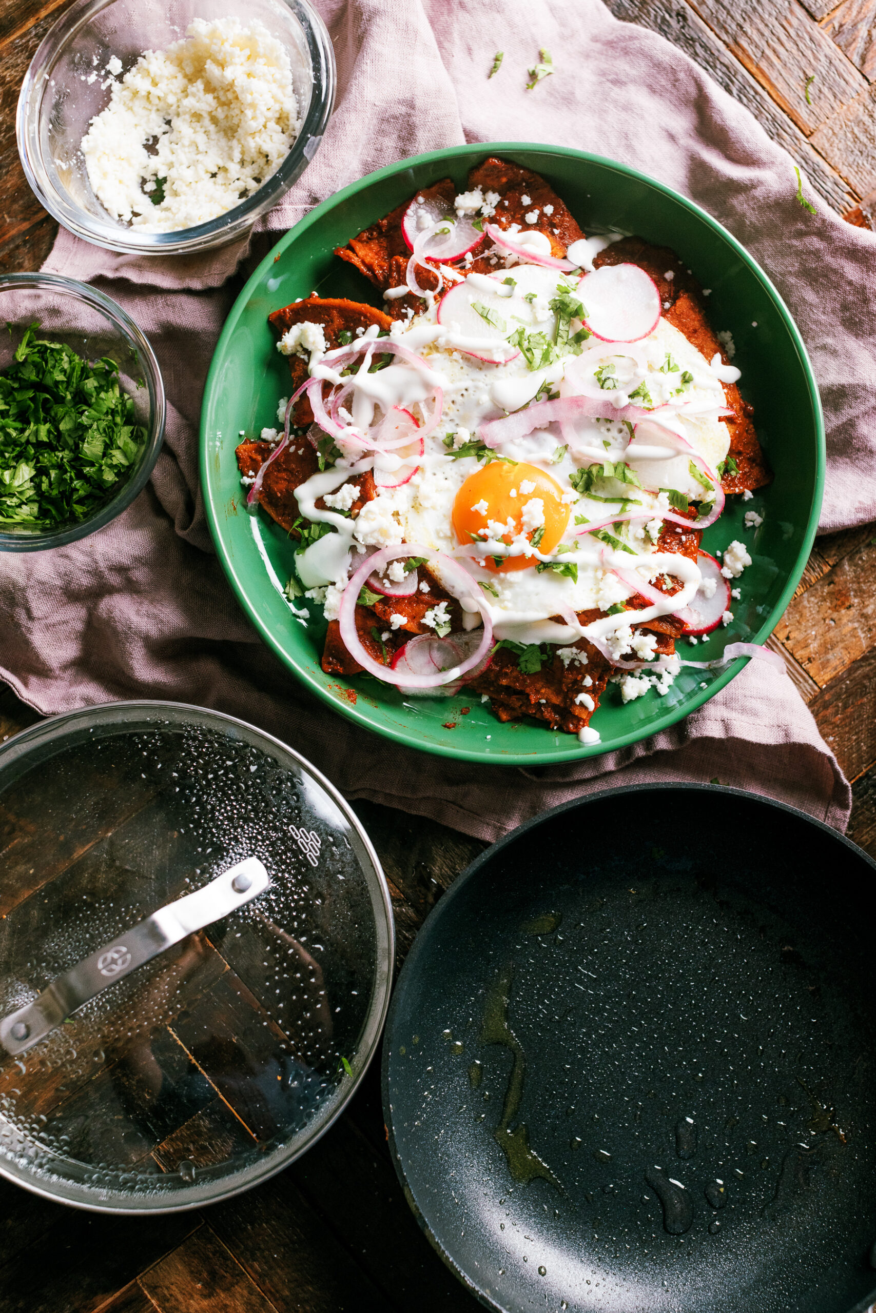 Chilaquiles with homemade tortilla chips, a from scratch guajillo and ancho pepper red sauce, then topped with a fried egg and garnishes.