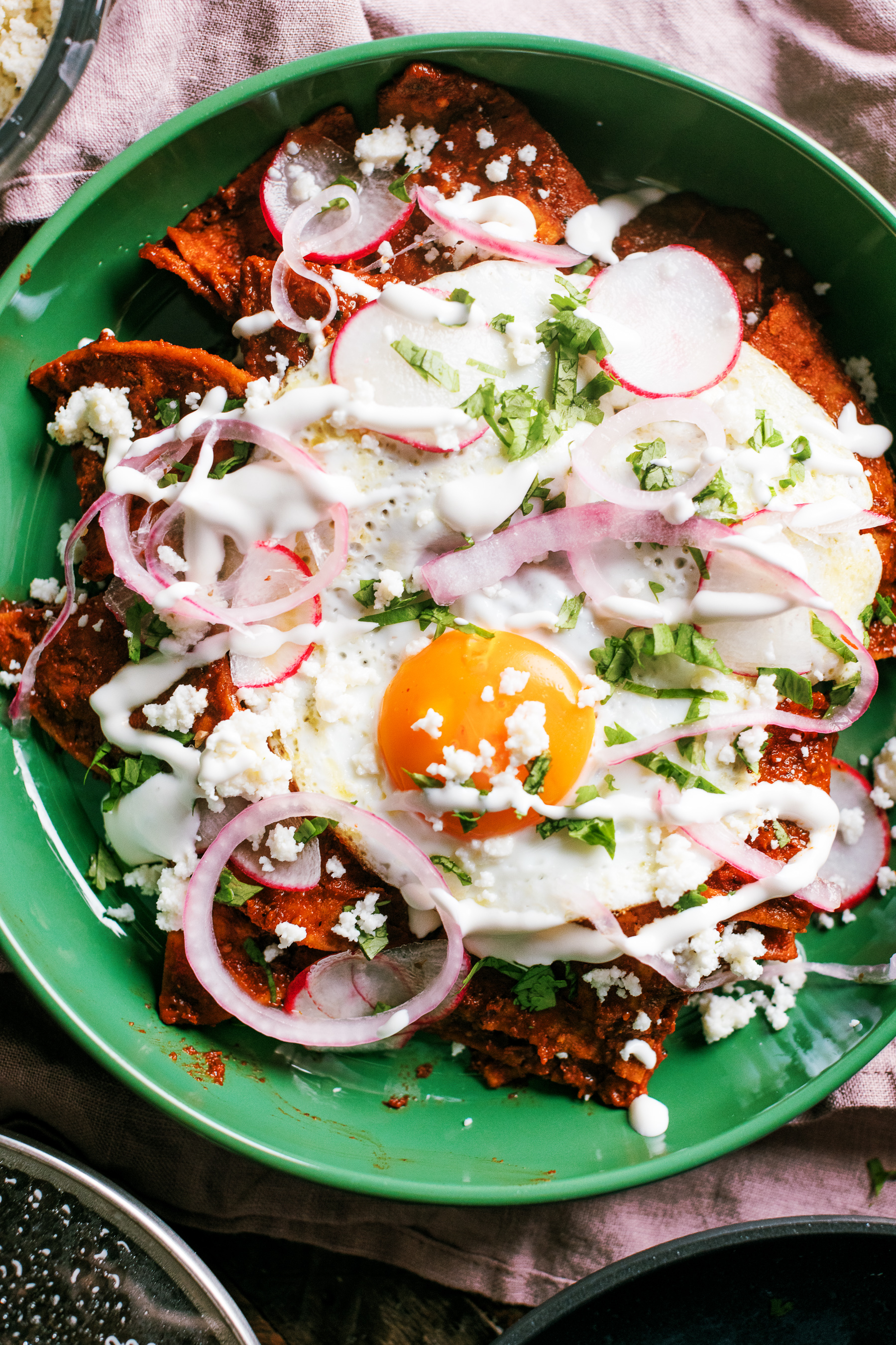 Chilaquiles with homemade tortilla chips, a from scratch guajillo and ancho pepper red sauce, then topped with a fried egg and garnishes.