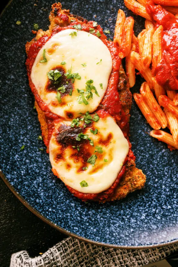 Air Fryer Chicken Parmesan coated with an Italian seasoned parmesan cheese breading. Air fried, then broiled with marinara and mozzarella.