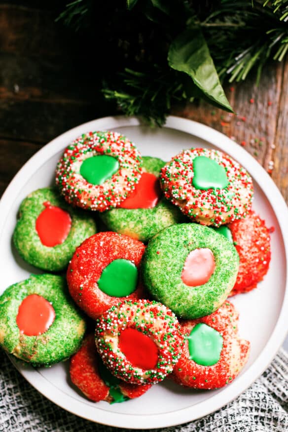 These crunchy thumbprint cookies with a hint of almond flavor are rolled in holiday sprinkles then filled with a little royal icing.