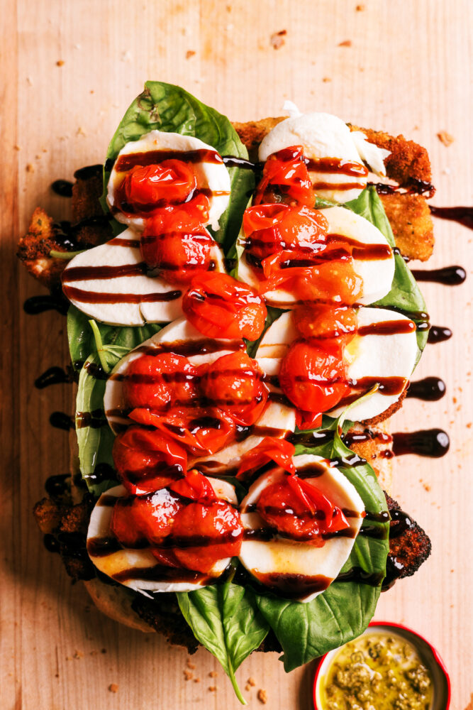 Crispy chicken Caprese sandwich with pesto, roasted tomatoes, fresh mozzarella, and balsamic glaze on toasted ciabatta bread.